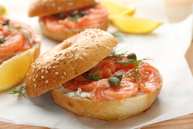 Tasty bagel with salmon on parchment closeup