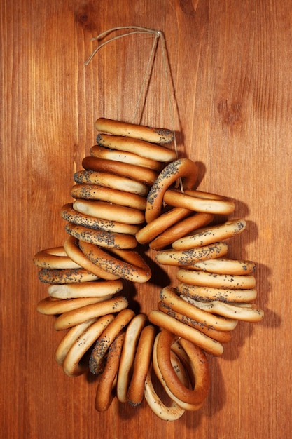 Tasty bagels on rope on wooden background