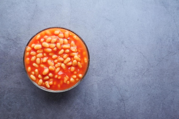 Tasty baked beans in a bowl on black background