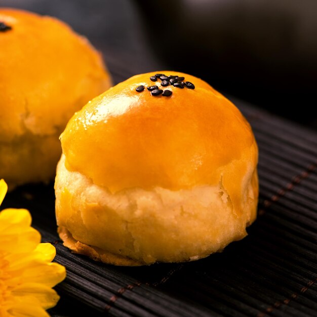 Tasty baked egg yolk pastry moon cake for midautumn festival on black slate dark background chinese festive food concept close up copy space