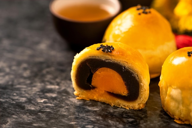 Tasty baked egg yolk pastry moon cake for MidAutumn Festival on black slate dark background Chinese festive food concept close up copy space