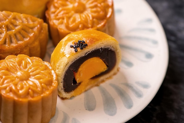 Tasty baked egg yolk pastry moon cake for MidAutumn Festival on black slate dark background Chinese festive food concept close up copy space