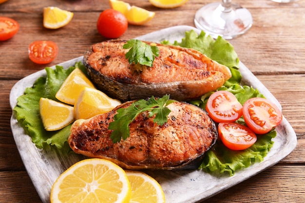 Tasty baked fish on plate on table closeup