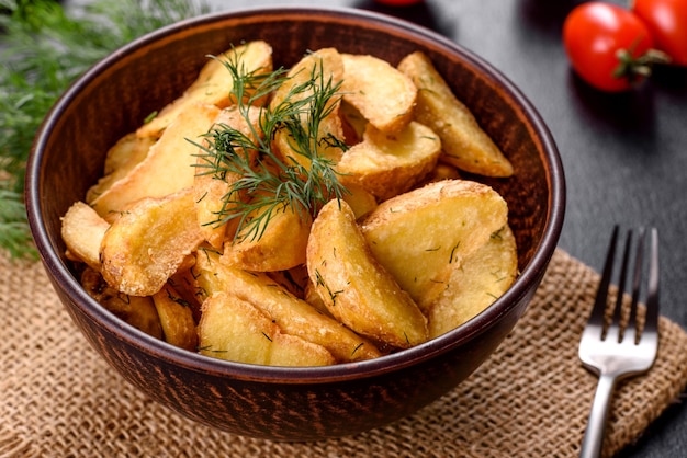 Tasty baked potatoes in a rustic way with spices and herbs in a brown deep plate. Unhealthy food