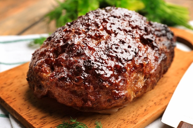 Tasty baked turkey meatloaf on wooden board closeup