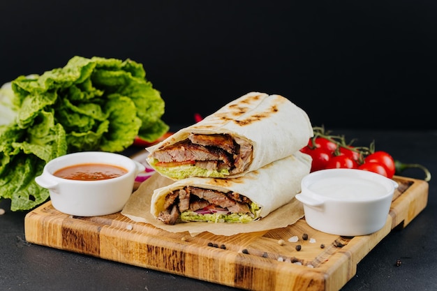 Tasty beef shawarma with fresh salad and vegetables lying on wooden board traditional arab dishes