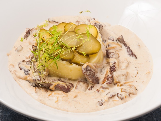 Tasty beef stroganoff with mashed potatoes on a white plate