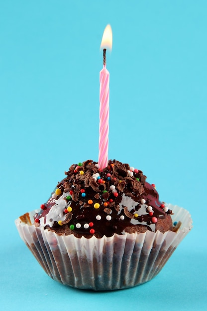 tasty birthday cupcake with candle on blue background