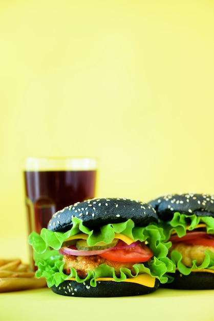 Tasty black burgers or hamburger served with french fries. Fast food for breakfast, lunch.