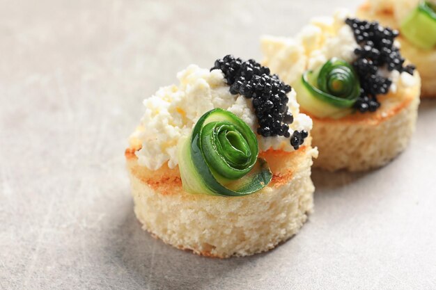 Tasty black caviar appetizer on grey background
