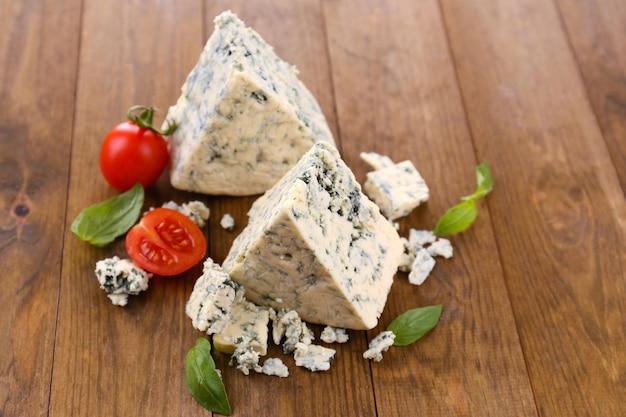 Tasty blue cheese with basil and tomato on wooden table