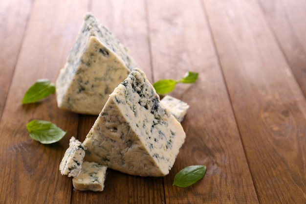 Tasty blue cheese with basil on wooden table