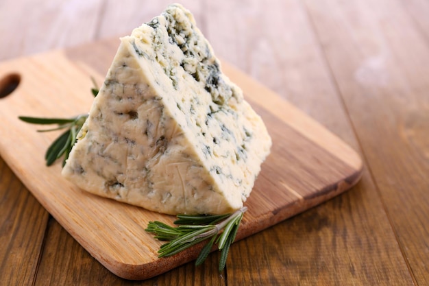 Tasty blue cheese with rosemary on wooden table