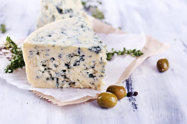 Tasty blue cheese with thyme and olives on wooden table