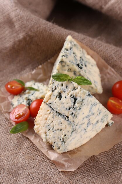 Tasty blue cheese with tomatoes and basil on burlap background