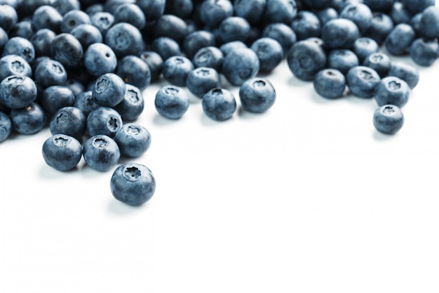 Tasty blueberries fruit are scattered on a white background