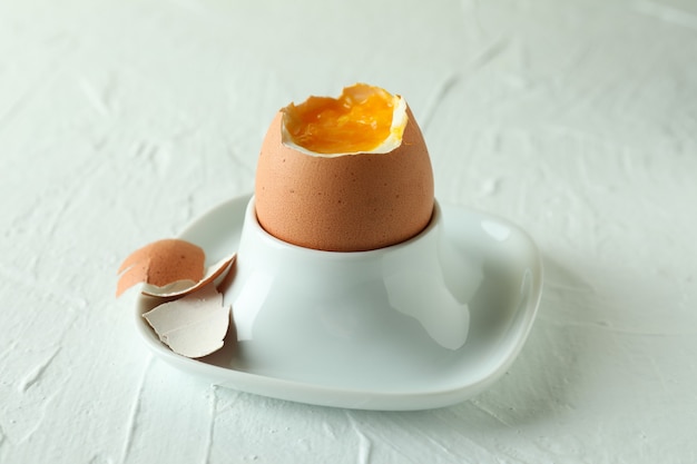 Tasty boiled egg on white textured, close up