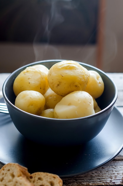 Tasty boiled potatoes in black bowl