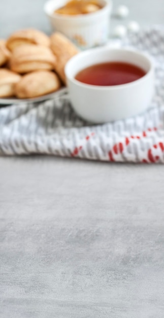 Tasty breakfast concept. Vertical banner with copy space and defocused cup of tea with sweet cinnamon cookies on surface. Shallow depth