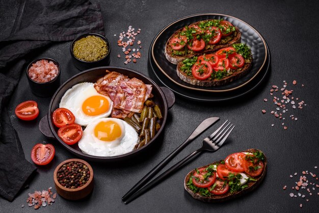 맛있는 아침 식사는 향신료와 허브를 곁들인 달걀 베이컨 콩 토마토로 구성되어 있습니다.