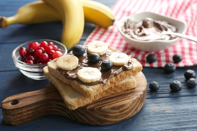 Tasty breakfast toasts with blueberries and banana on table