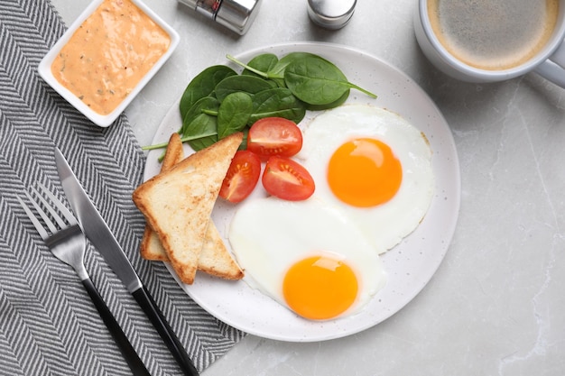 Tasty breakfast with fried eggs toasts and coffee served on light grey table flat lay