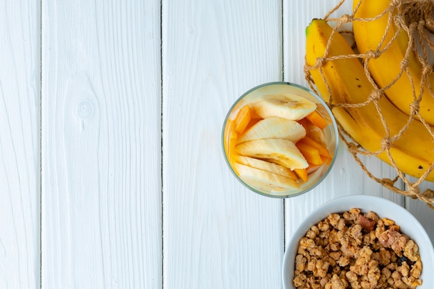 Tasty breakfast with granola, yoghurt and fruits in a glass bowl on wooden table