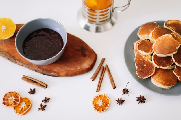 tasty breakfast with lush pancakes and teapot with spices cup of tea