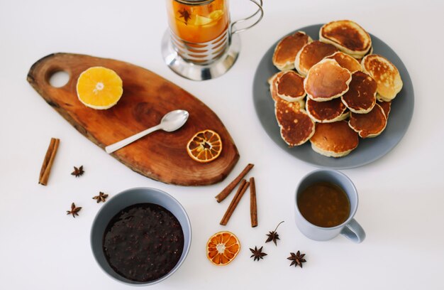 tasty breakfast with lush pancakes and teapot with spices cup of tea