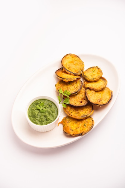 Gustoso brinjal pakora o frittelle di melanzane croccanti, snack indiano per l'ora del tè servito con chutney verde