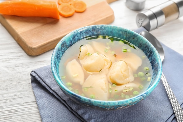 Tasty broth with dumplings on wooden table