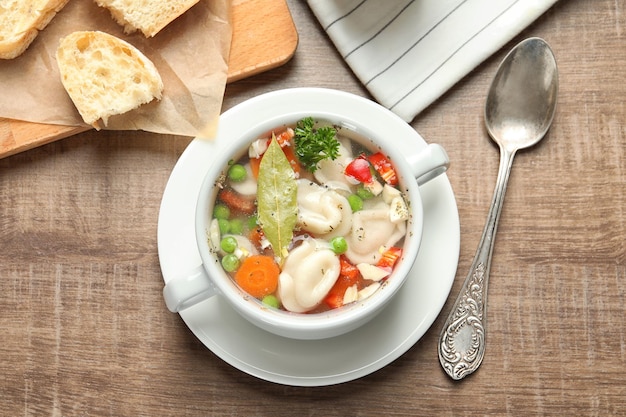 Tasty broth with dumplings on wooden table