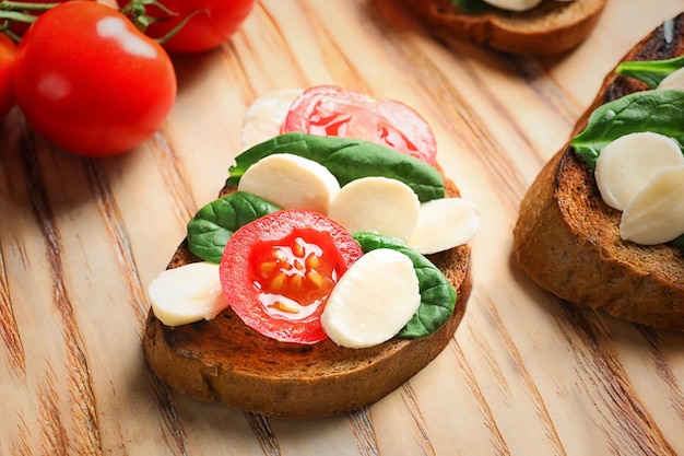 Tasty bruschetta with cherry tomatoes and mozzarella on wooden board