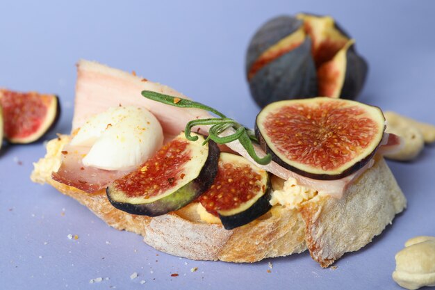 Tasty bruschetta with fig on violet background