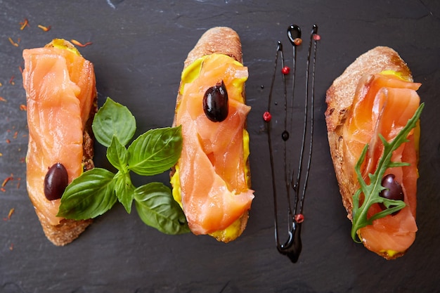 The tasty bruschetta with salmon on black stone