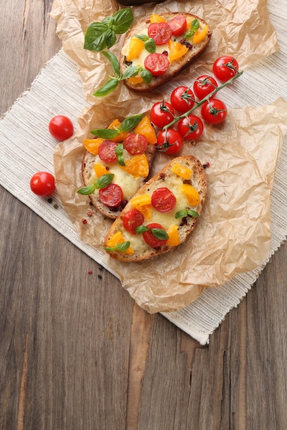 Tasty bruschetta with tomatoes on old wooden table