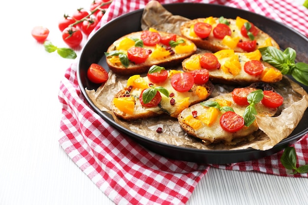 Tasty bruschetta with tomatoes in pan on table