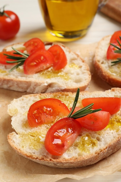 Tasty bruschettas with oil tomatoes and rosemary on parchment paper closeup