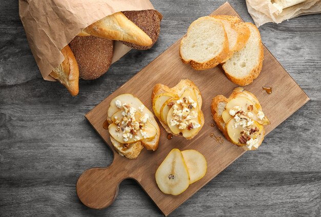 Photo tasty bruschettas with pear on wooden board top view