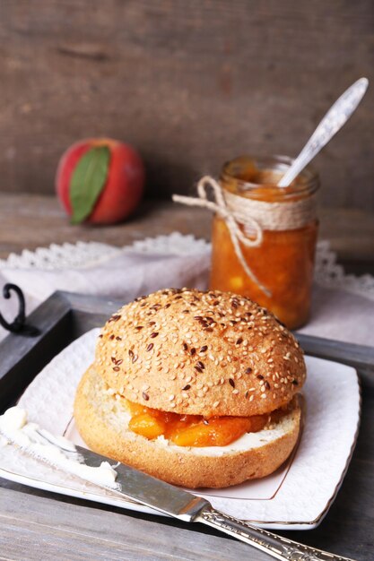 Tasty bun with homemade jam on wooden table