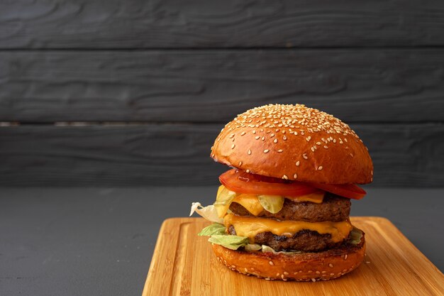 Tasty burger on black wooden surface close up