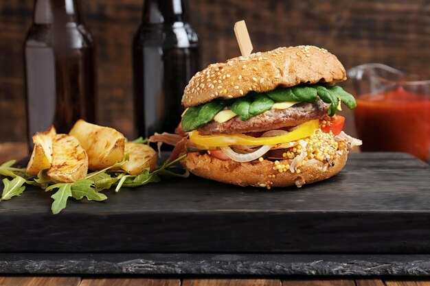 Tasty burger and potatoes on wooden board