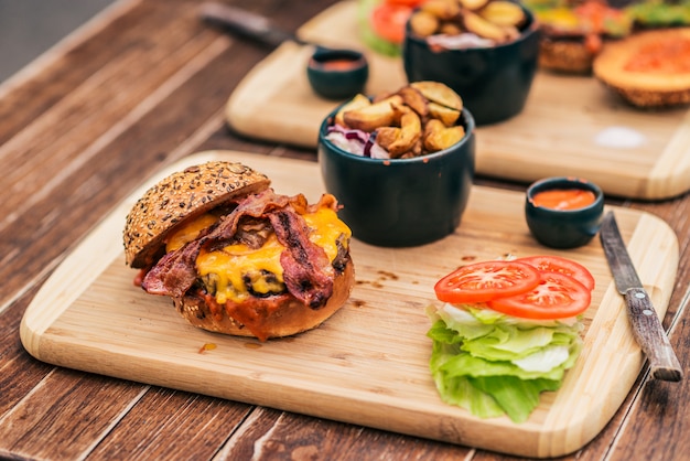 Gustoso hamburger con pancetta e un piatto di legno.