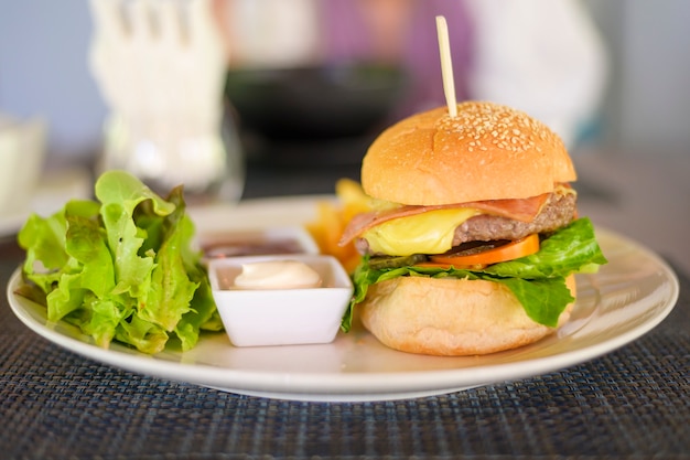 Tasty burger with beef served on a plate with sauces and lettuce