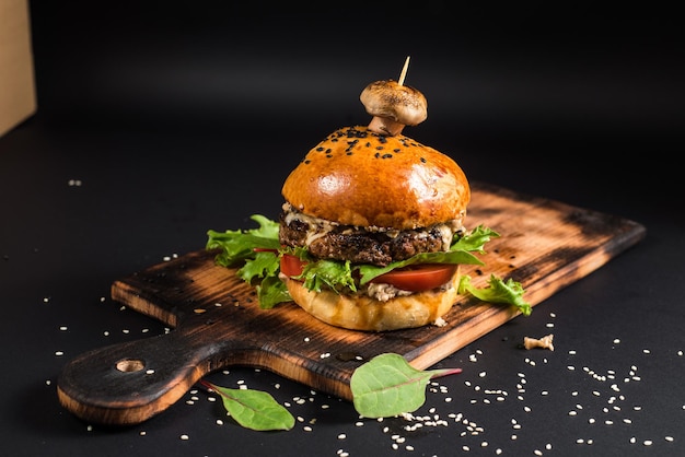 Tasty burger with grilled meat and mushroom on the black background