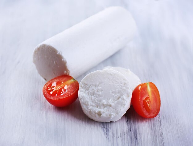 Tasty bushe cheese with tomato on wooden table