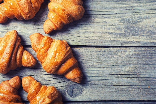 Tasty buttery croissants on old wooden table