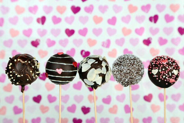 Tasty cake pops on color background