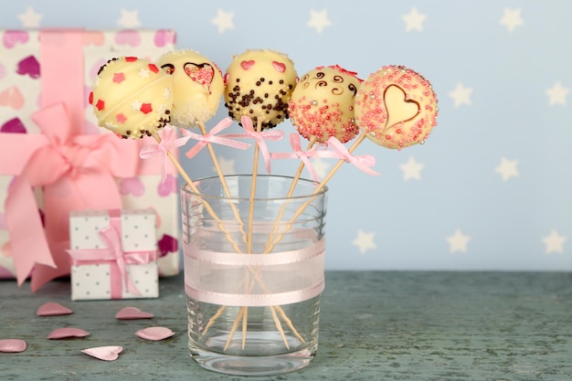 Tasty cake pops and gifts on blue background