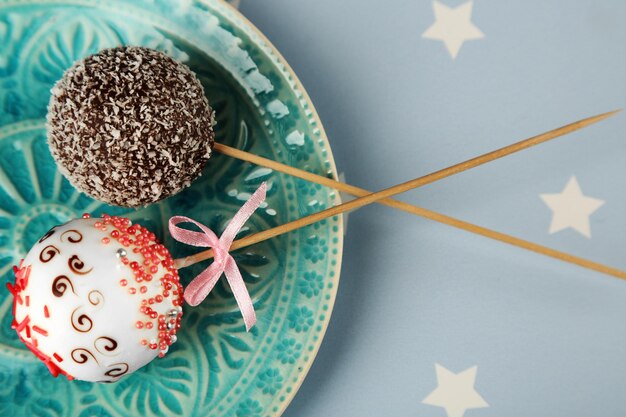 Tasty cake pops on plate, close up